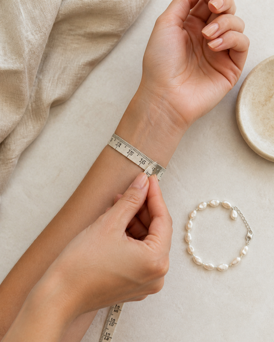 Measuring a bare wrist beside a pearl bracelet