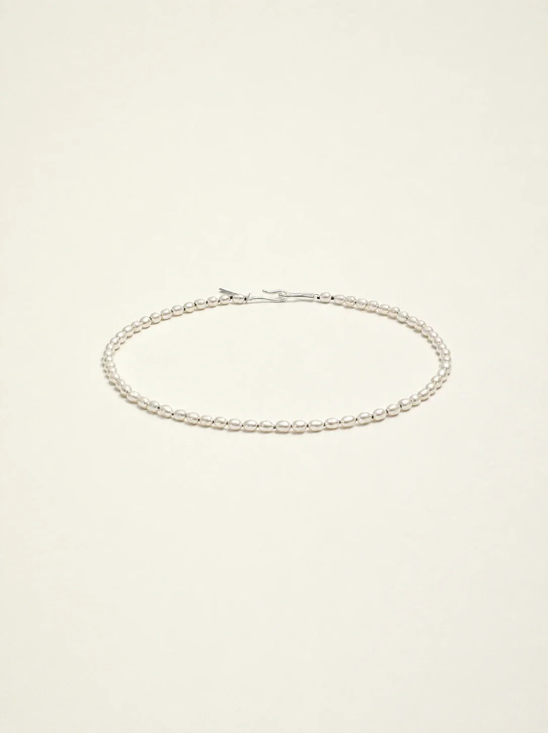 Cultured freshwater seed pearl choker necklace on a warm ivory background