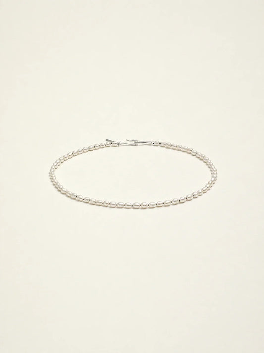 Cultured freshwater seed pearl choker necklace on a warm ivory background