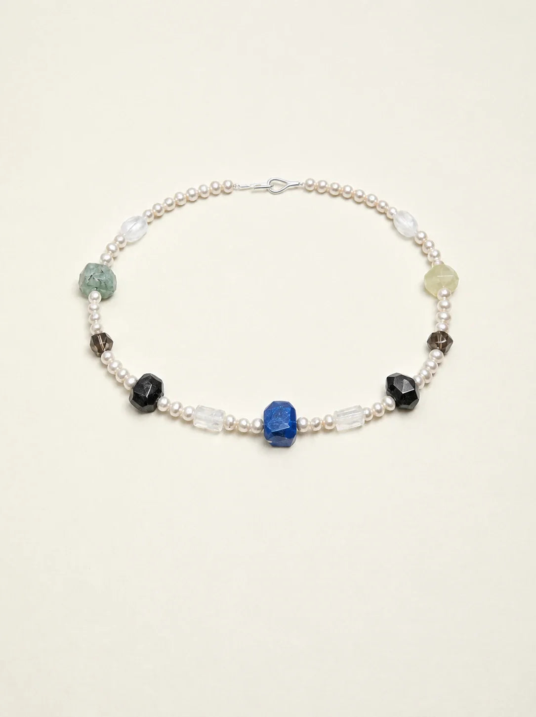 Natural gemstone and freshwater pearl necklace on warm ivory background