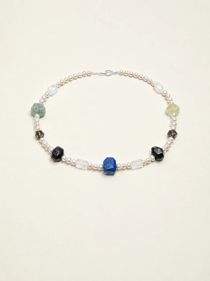 Natural gemstone and freshwater pearl necklace on warm ivory background