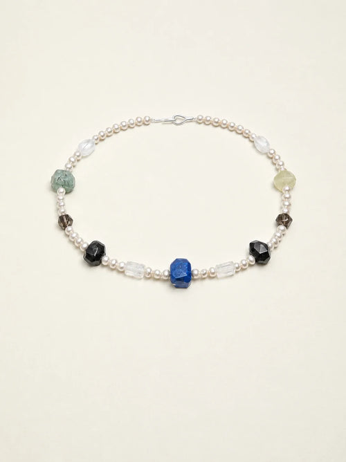 Natural gemstone and freshwater pearl necklace on warm ivory background