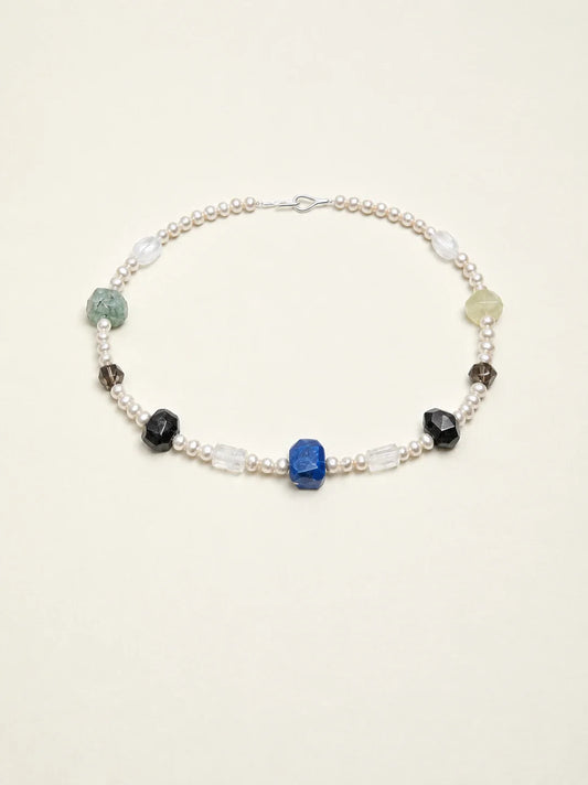 Natural gemstone and freshwater pearl necklace on warm ivory background