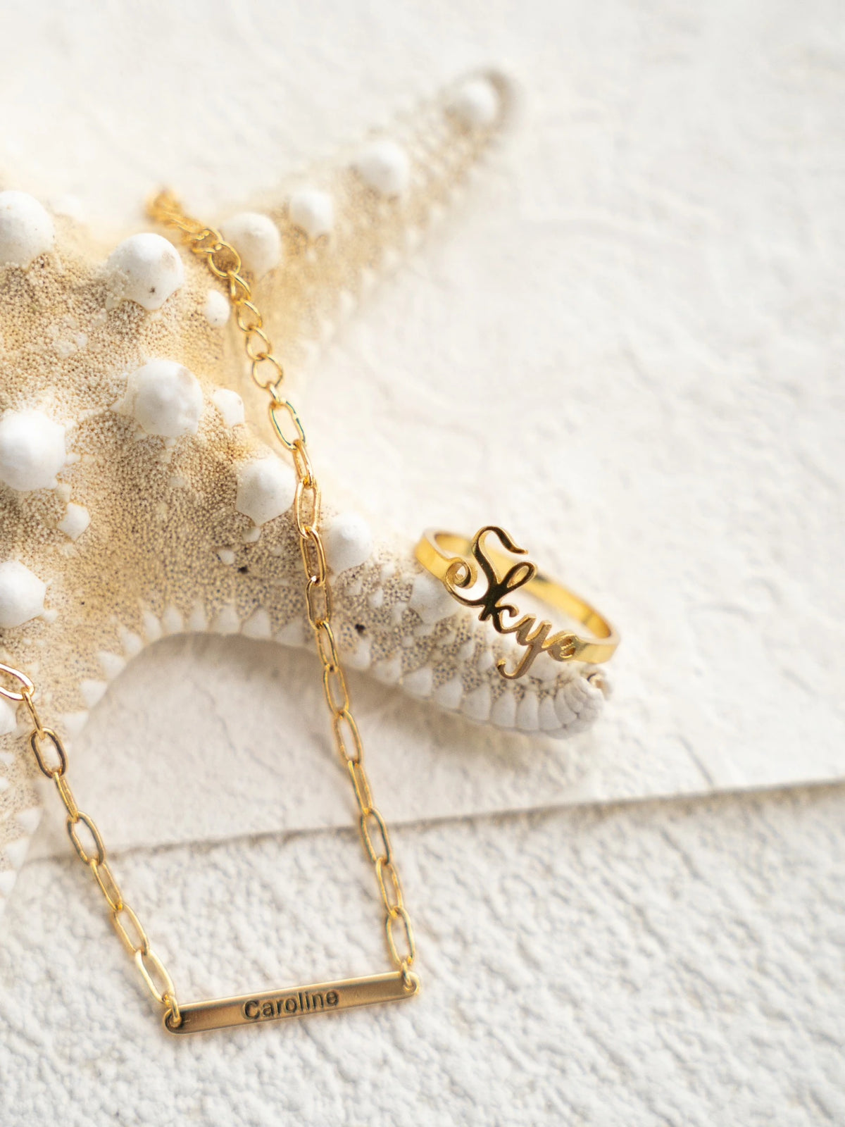 Gold Skye name ring styled beside a separate personalized necklace