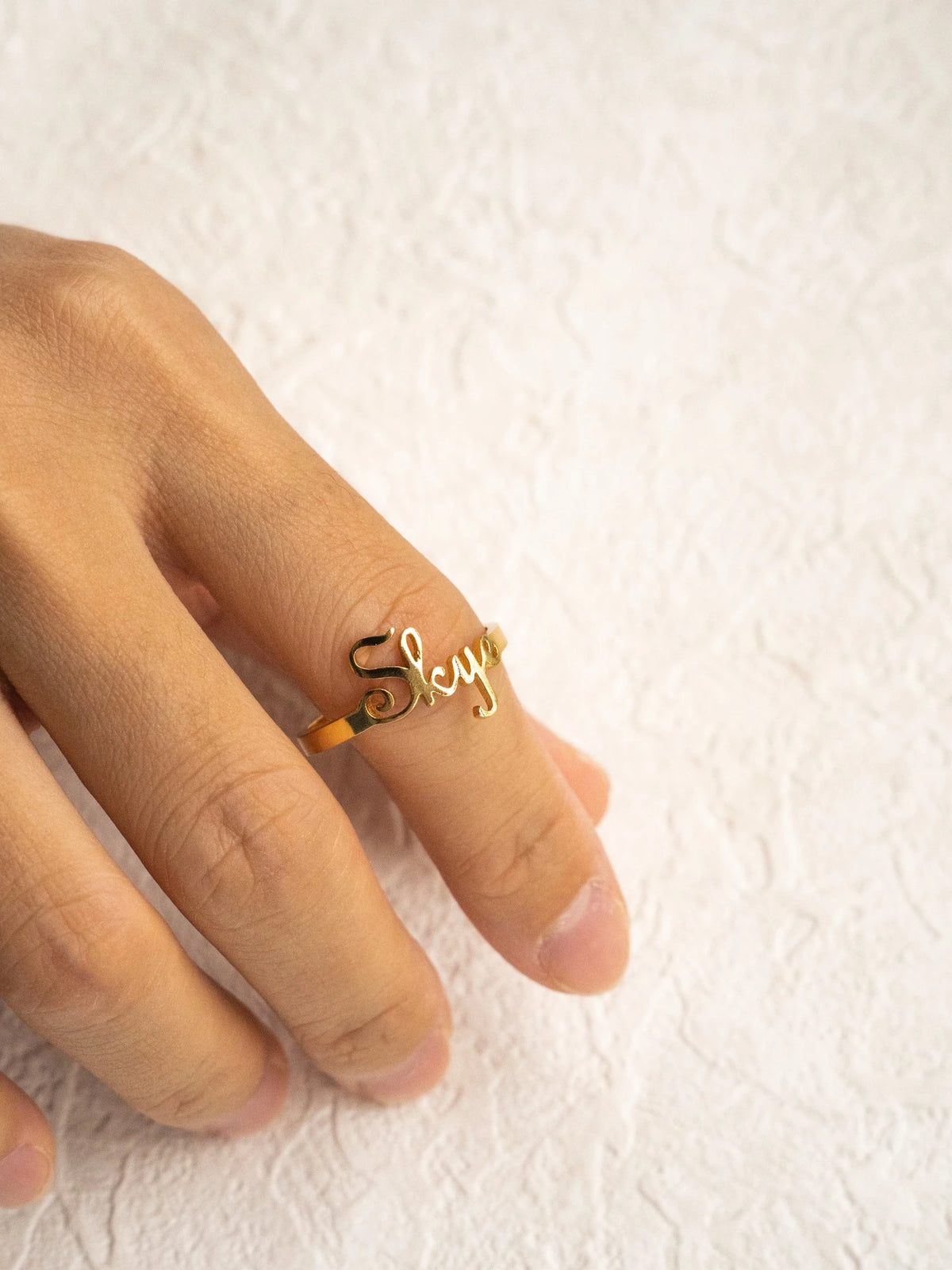 Gold Skye name ring worn on a finger