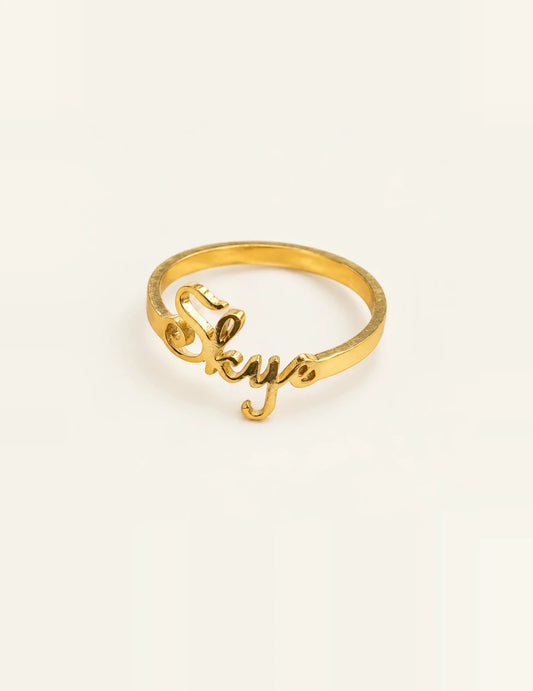 Gold vermeil personalized name ring with Skye cutout lettering on an ivory background