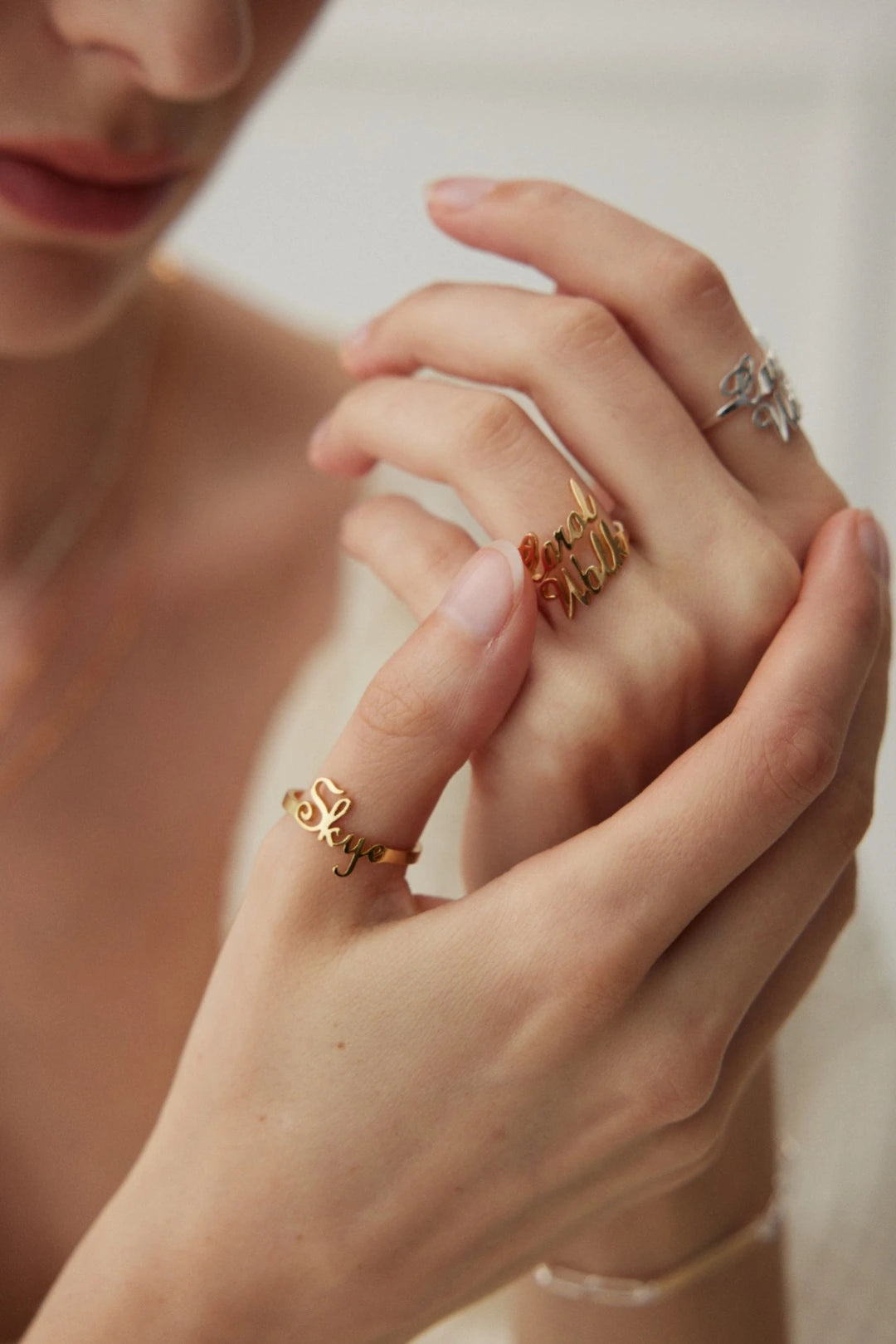 Model wearing a gold Skye name ring alongside gold and silver name rings