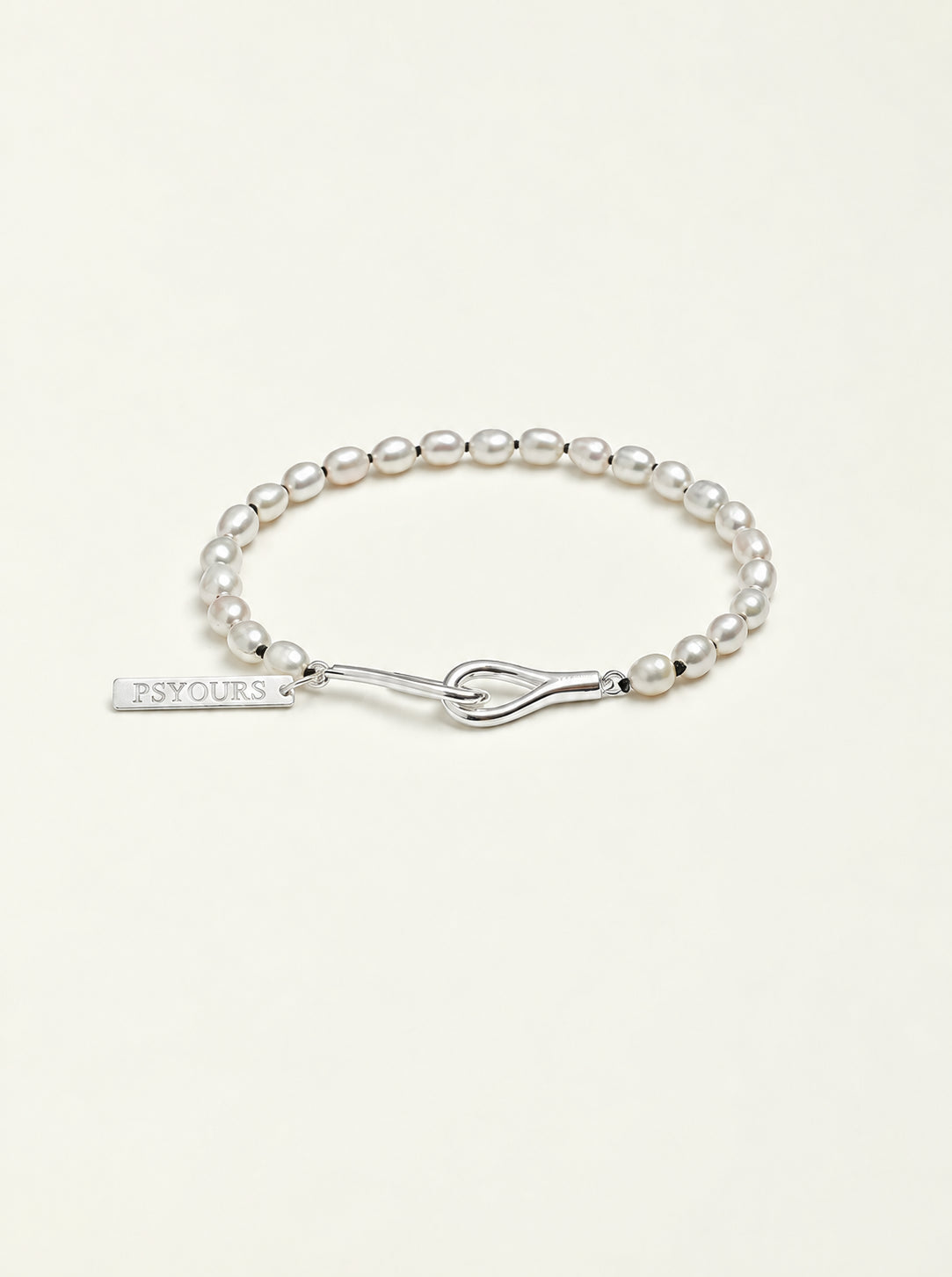 Freshwater pearl bracelet with a sterling silver open clasp and PSYOURS name tag on a pale warm ivory background