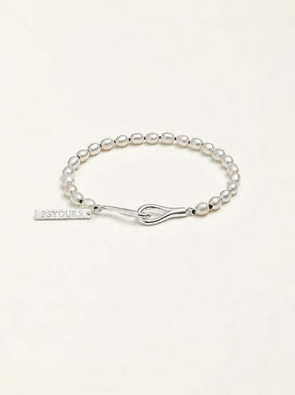 Freshwater pearl bracelet with a sterling silver open clasp and PSYOURS name tag on a pale warm ivory background