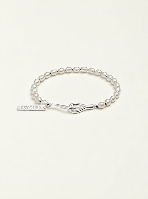 Freshwater pearl bracelet with a sterling silver open clasp and PSYOURS name tag on a pale warm ivory background