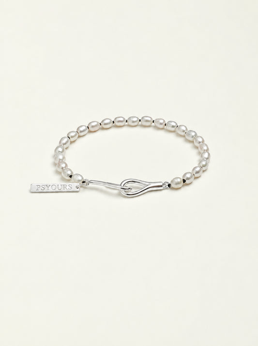Freshwater pearl bracelet with a sterling silver open clasp and PSYOURS name tag on a pale warm ivory background