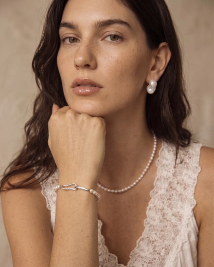 Model wearing the freshwater pearl bracelet with sculptural sterling silver open clasp