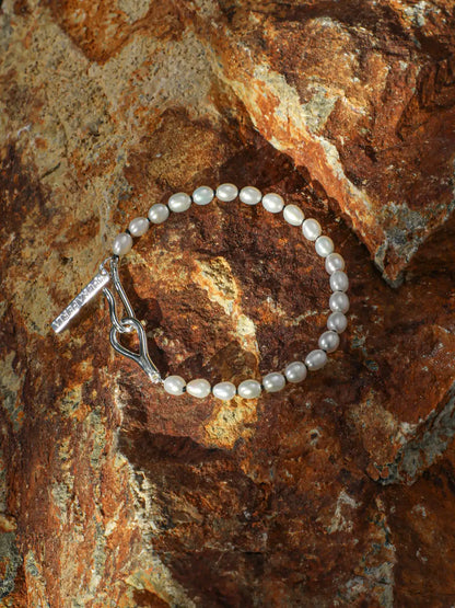 Freshwater pearl bracelet with sterling silver open clasp displayed on natural rock