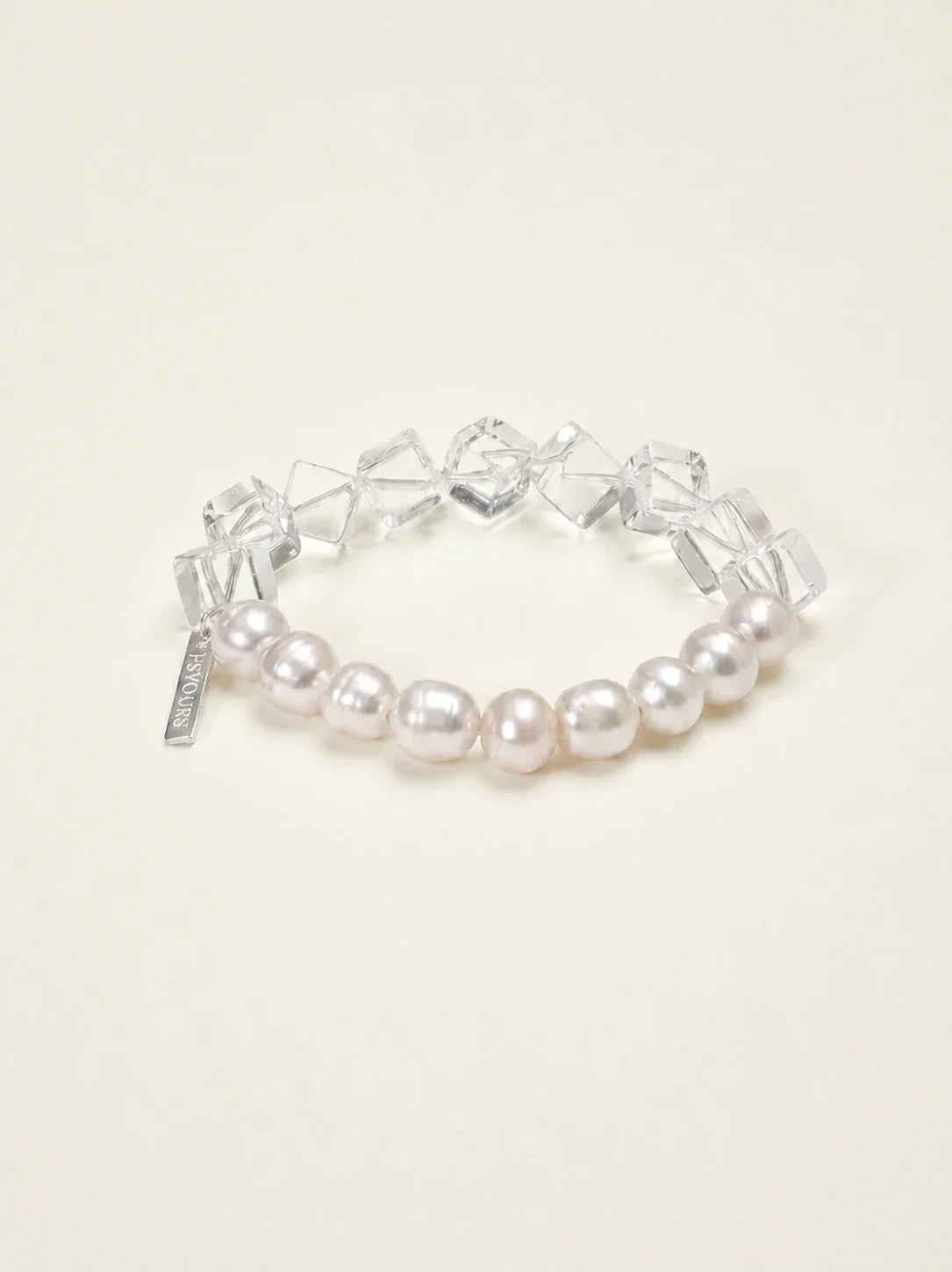 Freshwater pearl and geometric clear quartz bracelet on warm ivory background