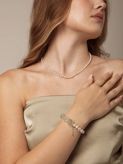 Model wearing a freshwater pearl and clear quartz beaded bracelet with a beige satin outfit