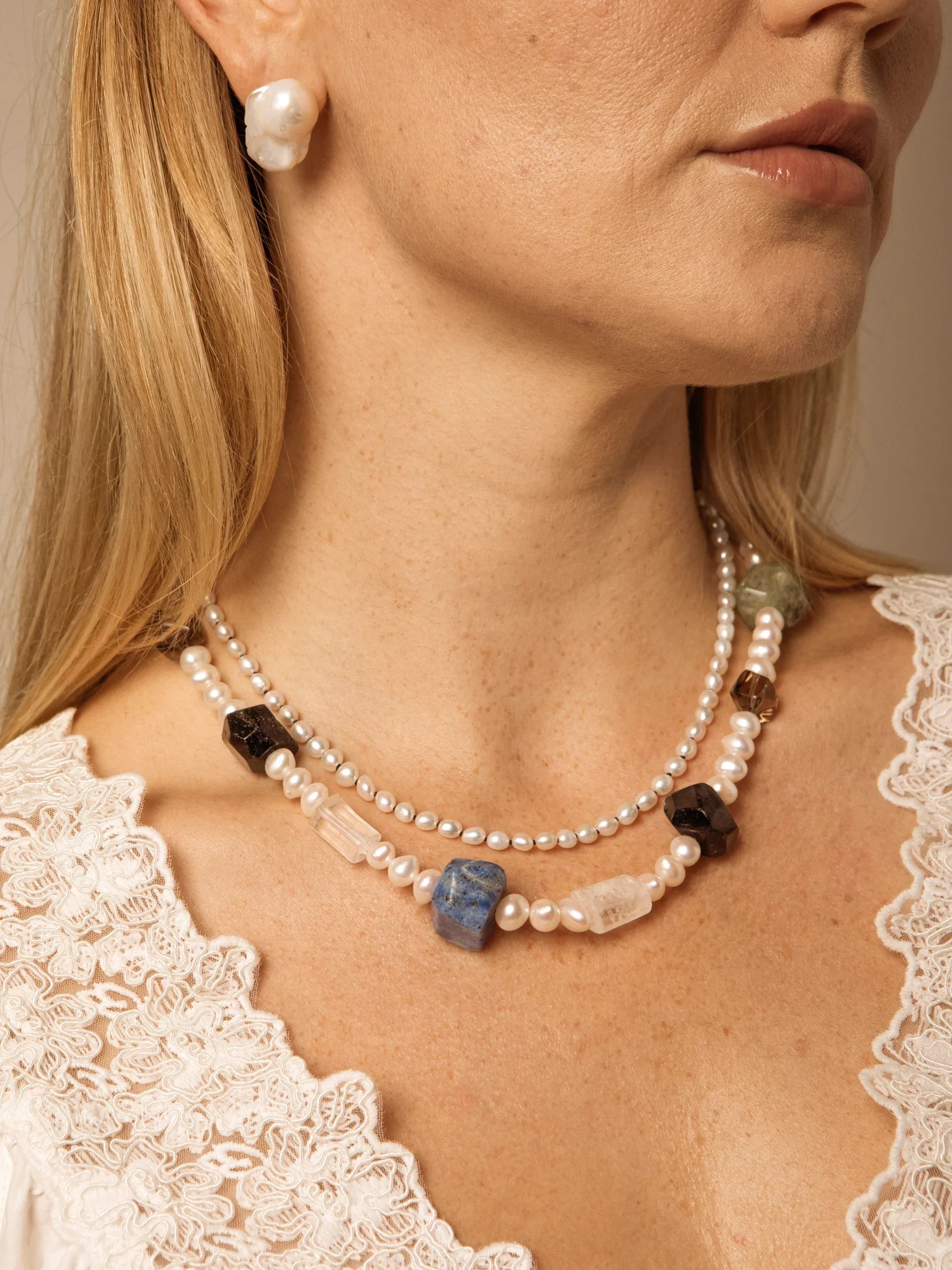 Styling image with pearl earrings and layered necklaces; earrings are not included