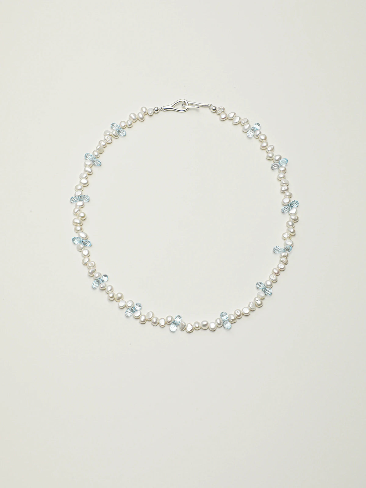 Blue topaz and baroque pearl necklace with 925 silver details on a light background