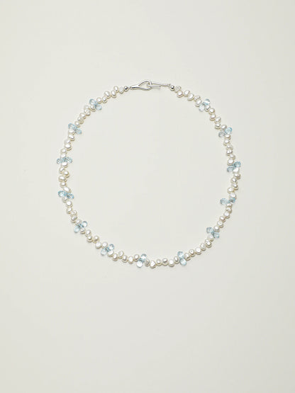 Blue topaz and baroque pearl necklace with 925 silver details on a light background