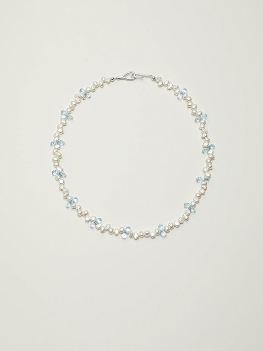 Blue topaz and baroque pearl necklace with 925 silver details on a light background