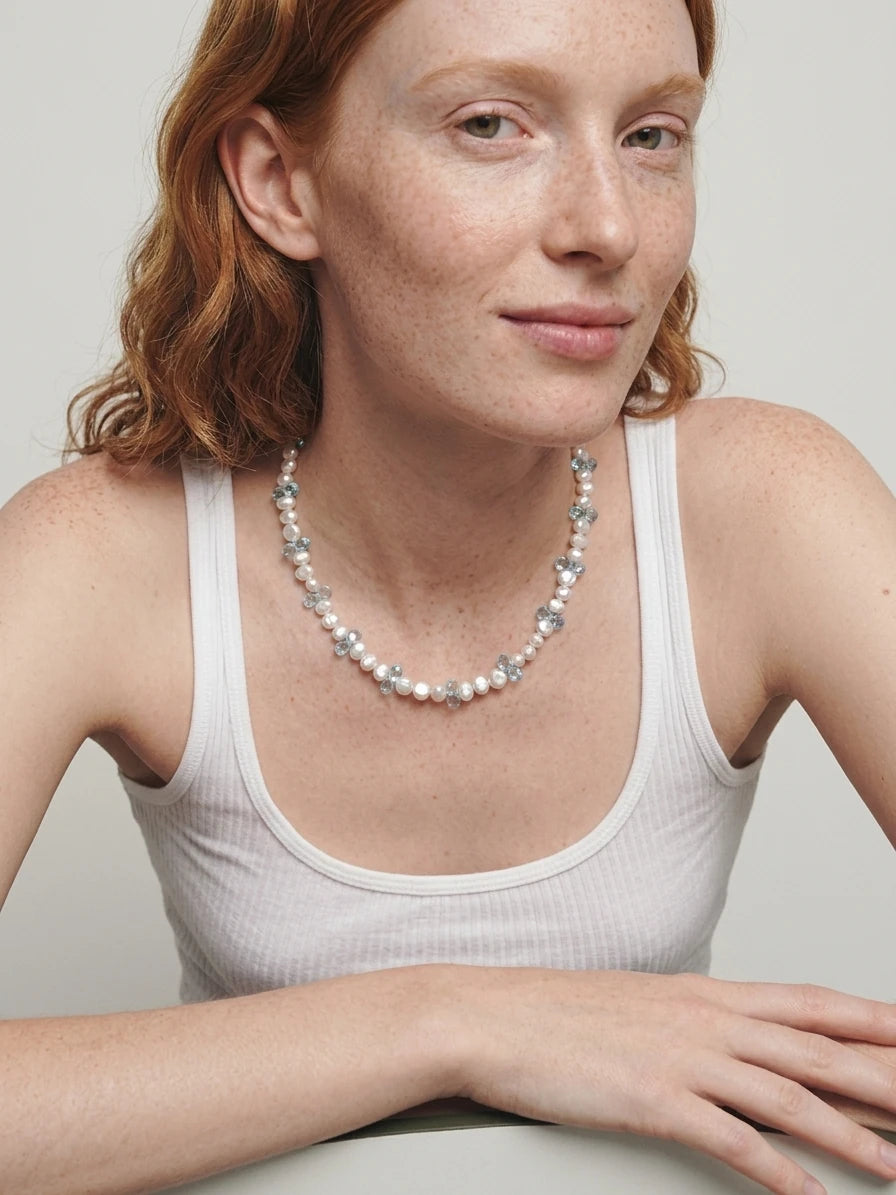 Styling reference of the blue topaz and pearl necklace worn with a white top
