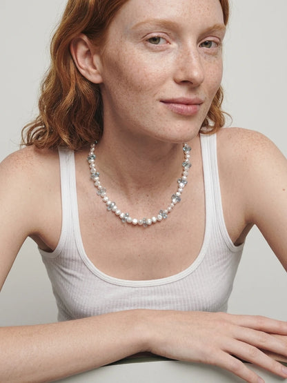 Styling reference of the blue topaz and pearl necklace worn with a white top