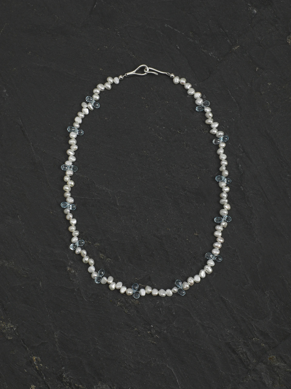 Full view of the 46 cm pearl and blue topaz necklace on a dark background