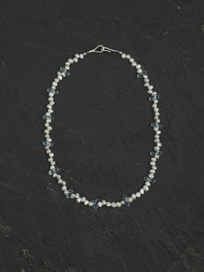 Full view of the 46 cm pearl and blue topaz necklace on a dark background