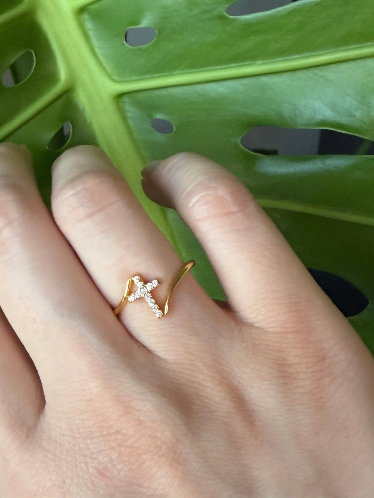 Close-up of the gold cross bypass ring with sparkling CZ stones worn on a finger