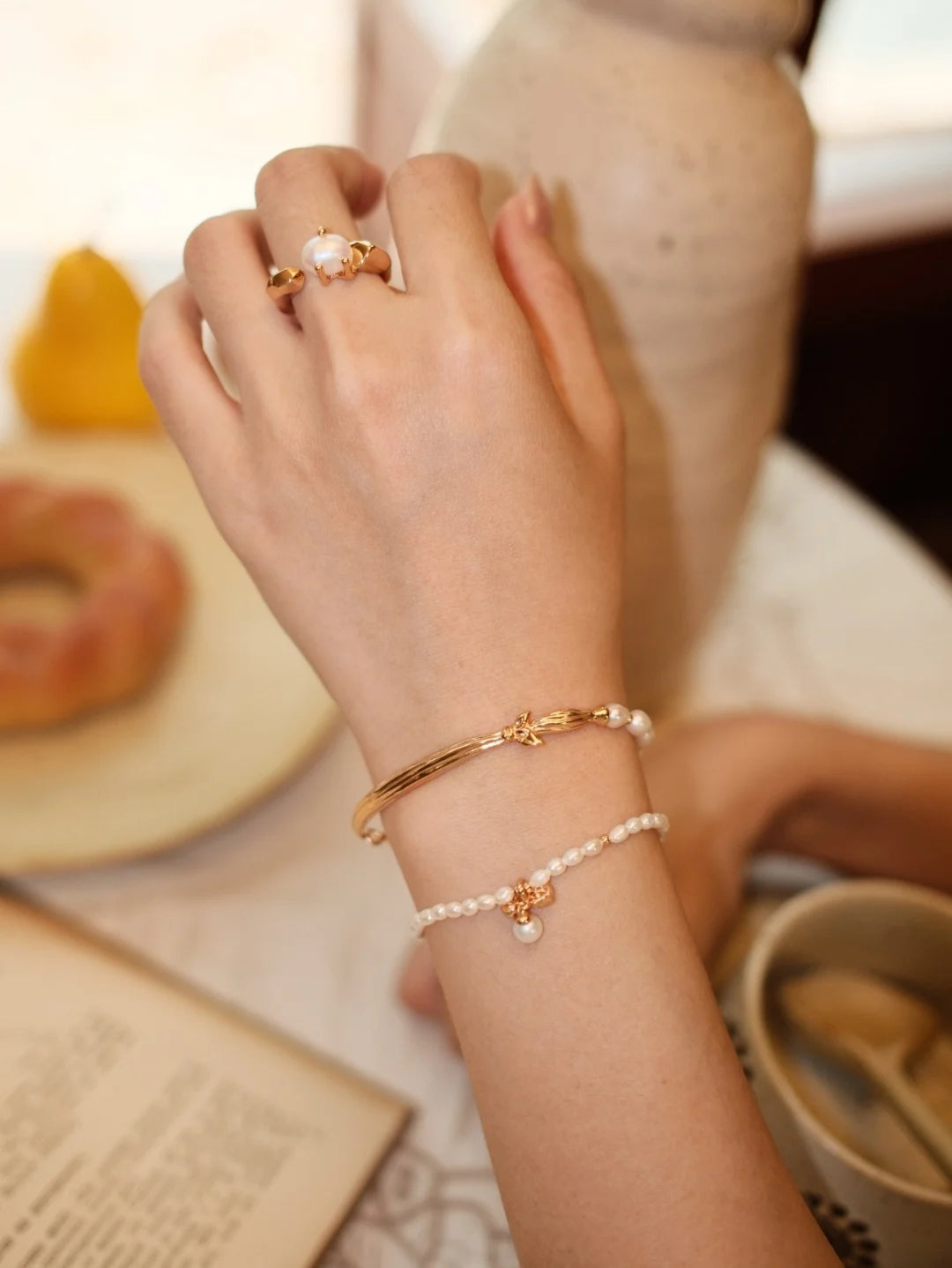 Faceted Pearl Claw Open Ring in gold worn with pearl and gold bracelets
