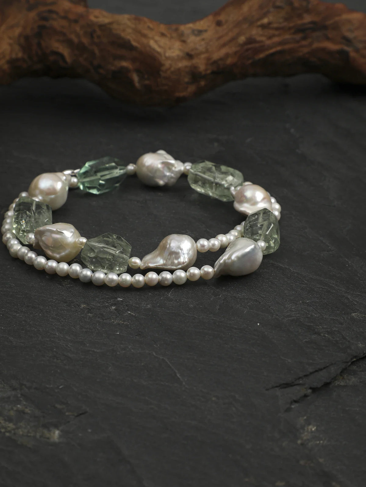 Baroque pearl and freeform green quartz necklace coiled on slate