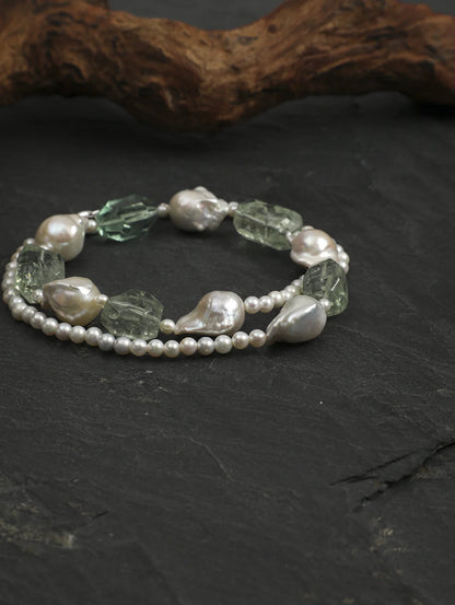 Baroque pearl and freeform green quartz necklace coiled on slate