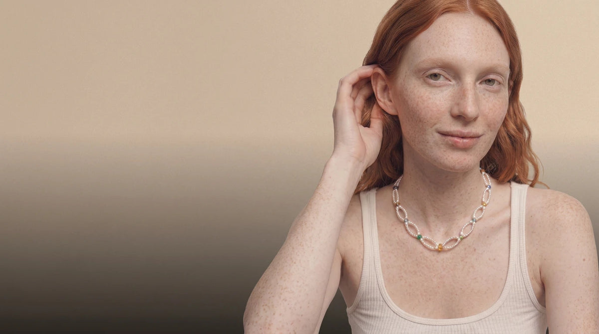 Woman with red hair wearing a baroque pearl and gemstone necklace