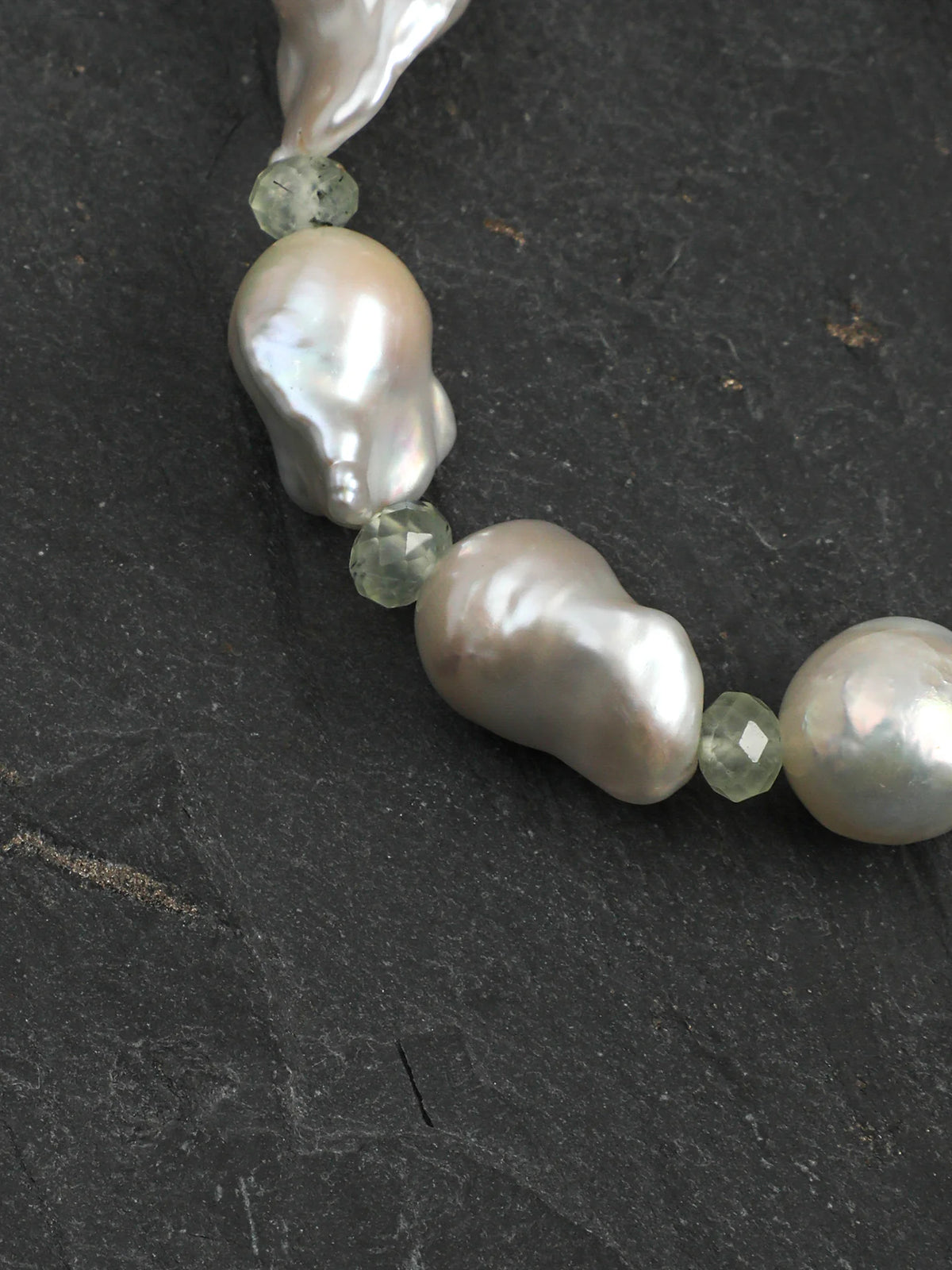 Psyours Misty Green bracelet styled on driftwood, showing the sterling silver logo tag