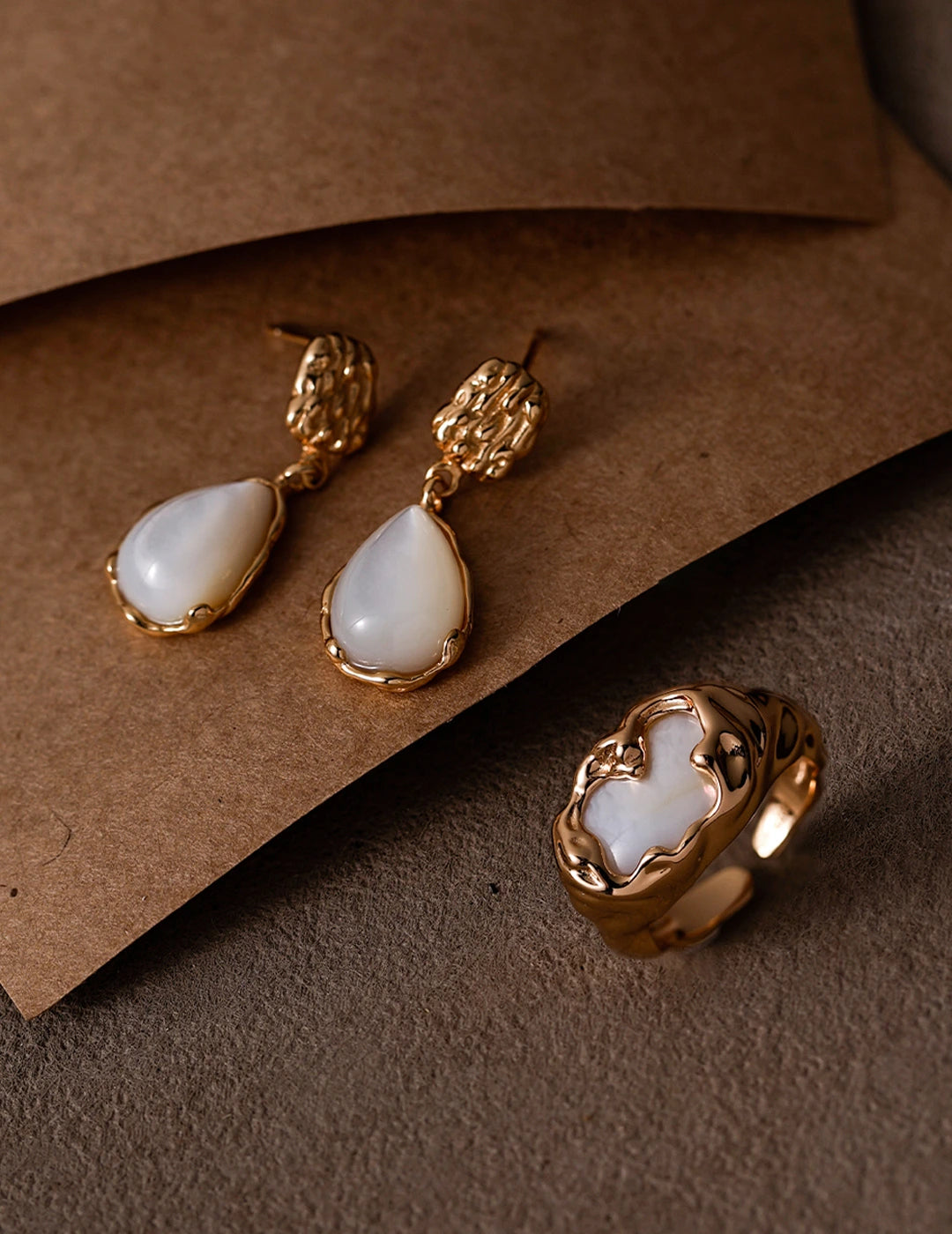 Molten Mother-of-Pearl Open Ring styled with matching earrings on a warm textured background