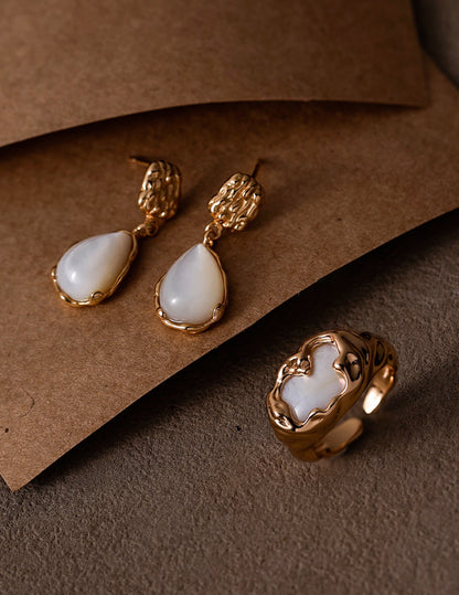Molten Mother-of-Pearl Open Ring styled with matching earrings on a warm textured background