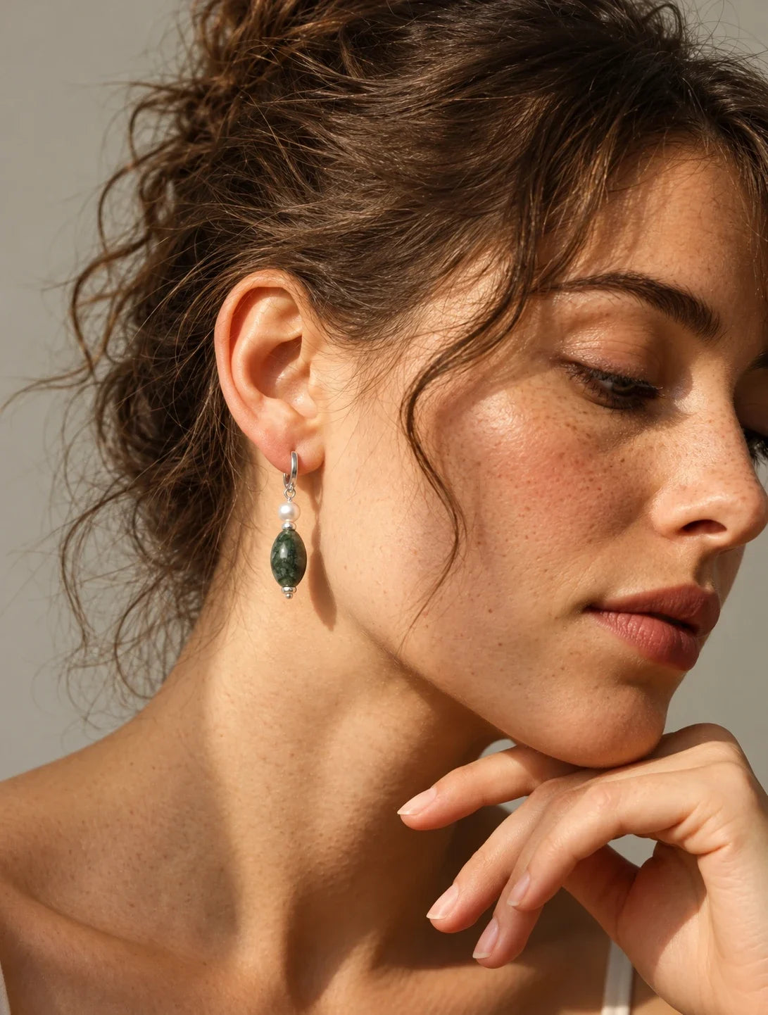 Model wearing a moss agate and pearl drop earring, side view