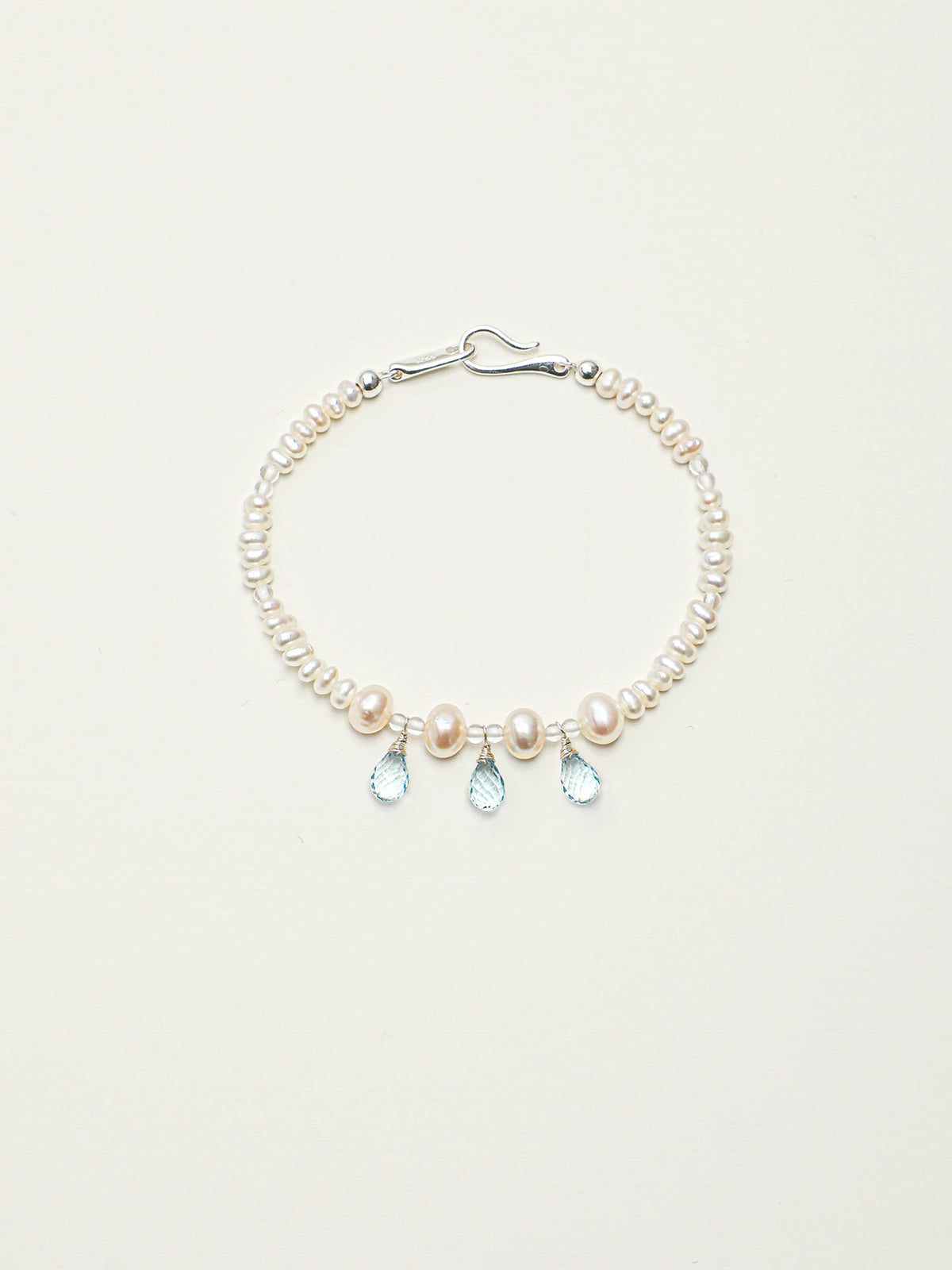 Ocean Tears pearl and blue topaz bracelet with silver hook clasp on a light background