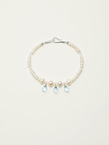 Ocean Tears pearl and blue topaz bracelet with silver hook clasp on a light background
