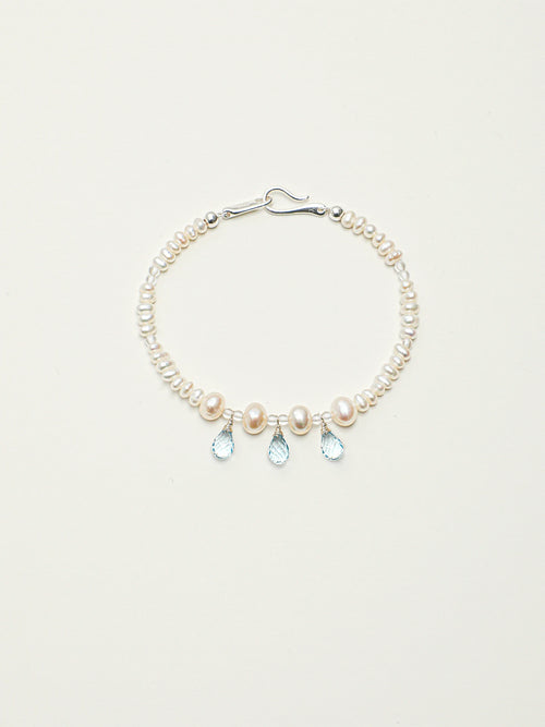 Ocean Tears pearl and blue topaz bracelet with silver hook clasp on a light background