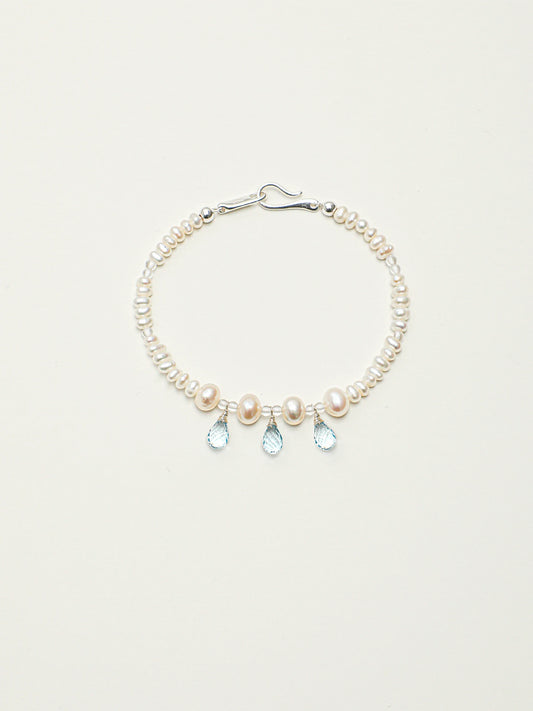 Ocean Tears pearl and blue topaz bracelet with silver hook clasp on a light background