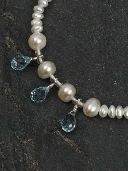 Close-up of three dangling teardrop-cut blue topaz gems and pearls on the Ocean Tears bracelet