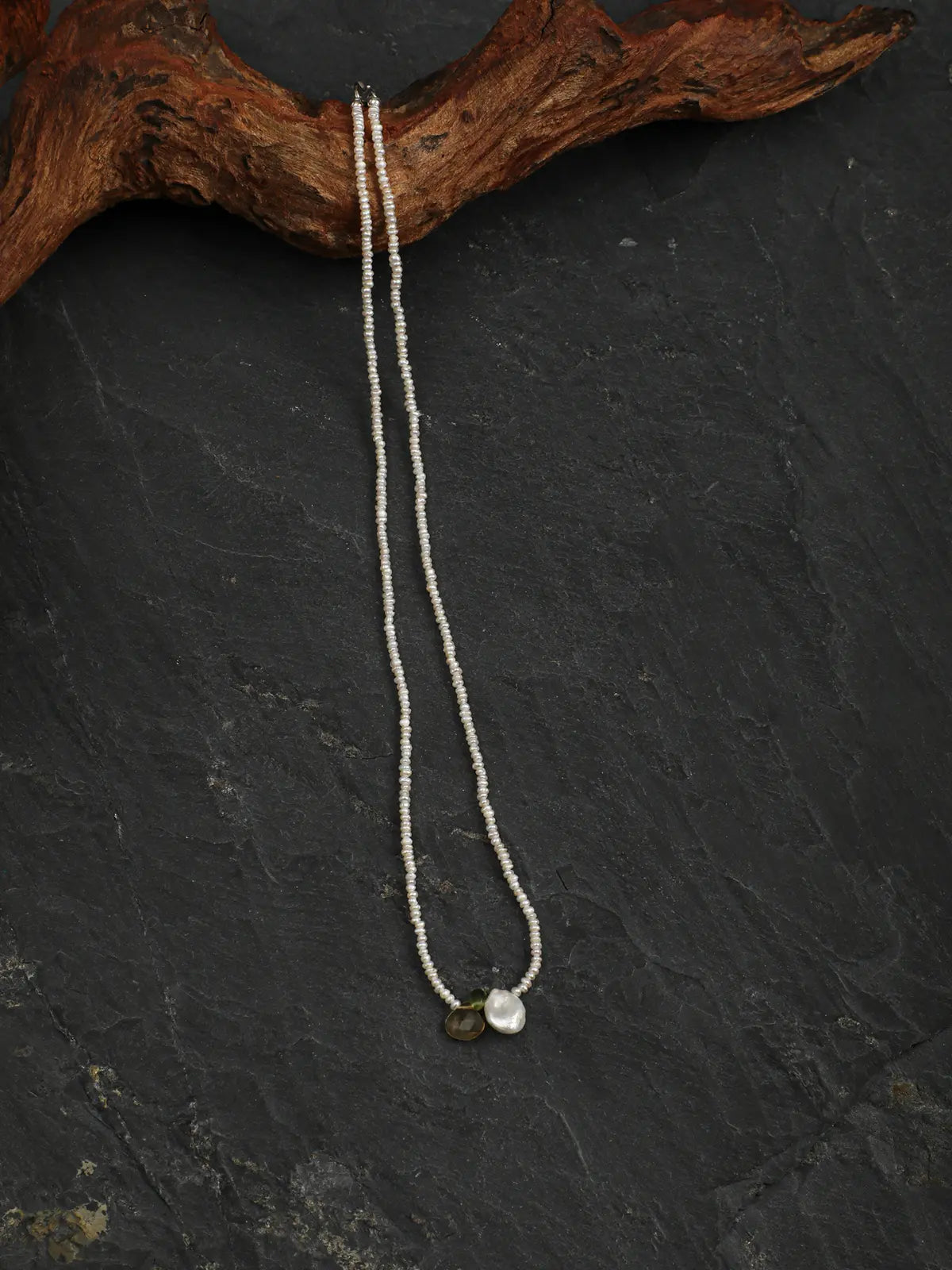 Full pearl necklace displayed against dark stone and wood