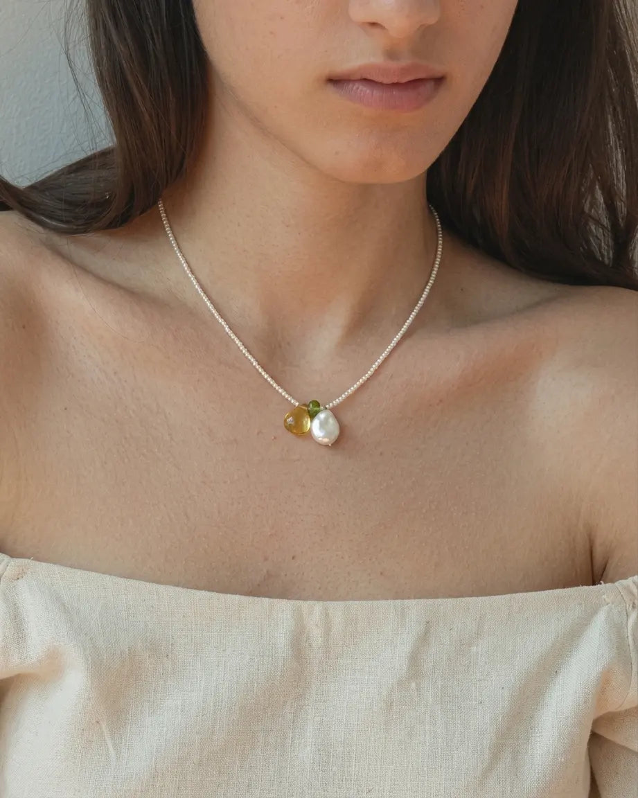 Illustrative styling image of the pearl necklace worn at the neckline