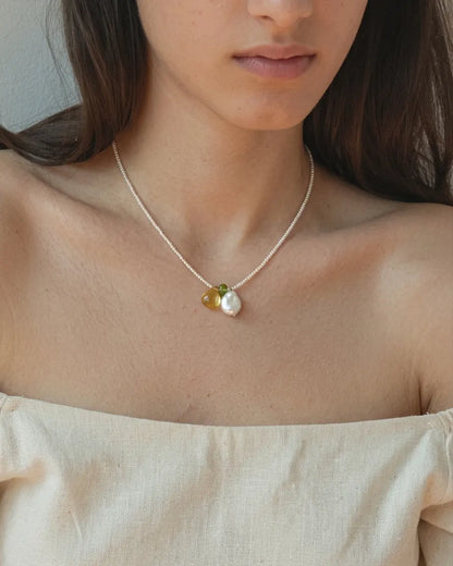 Illustrative styling image of the pearl necklace worn at the neckline