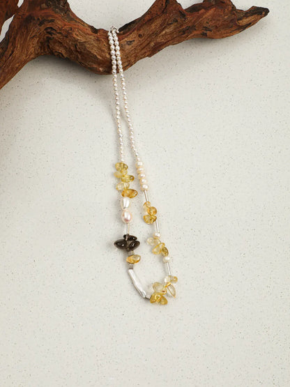Golden Sunlight pearl and gemstone necklace draped over wood