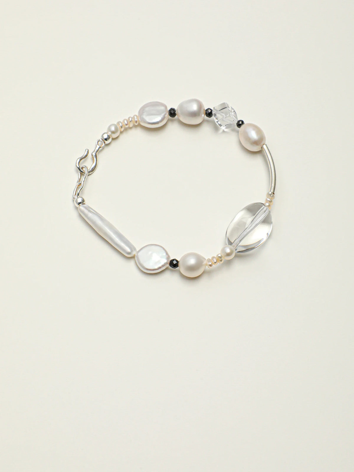 Psyours Pure Radiance baroque pearl and black tourmaline bracelet, flat lay on cream background
