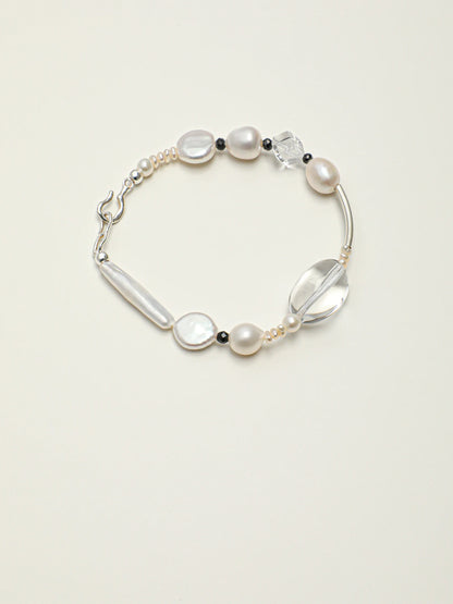 Psyours Pure Radiance baroque pearl and black tourmaline bracelet, flat lay on cream background