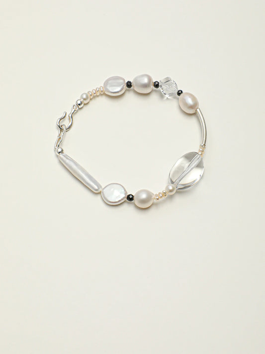 Psyours Pure Radiance baroque pearl and black tourmaline bracelet, flat lay on cream background