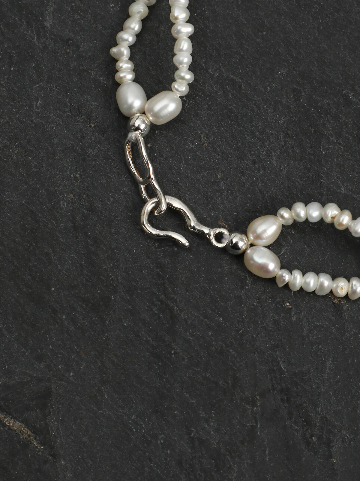 Close-up of the woven pearl lace and colored gemstone accents
