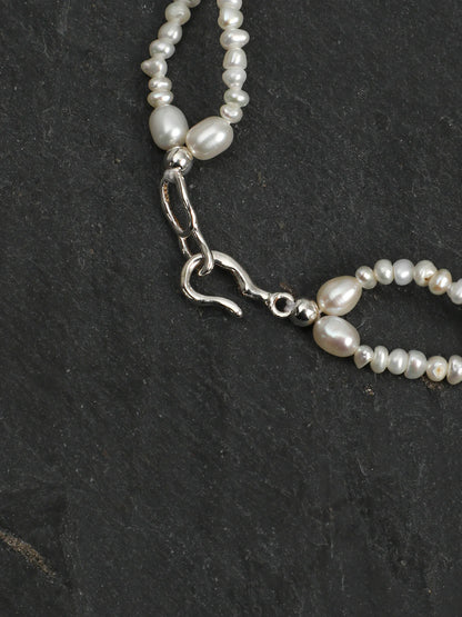 Close-up of the woven pearl lace and colored gemstone accents